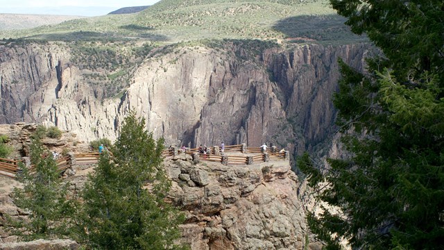 people standing at an overlook perched on a peninsula jutting into the Black Canyon