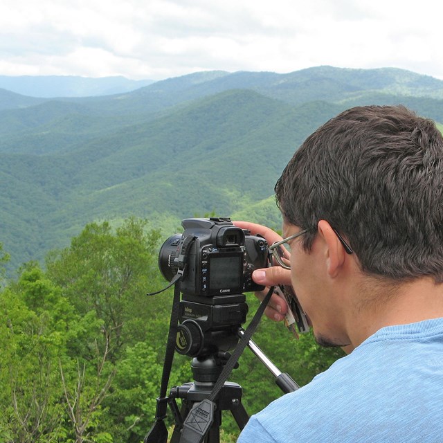 Two men looking at the back of a camera at an overlook.