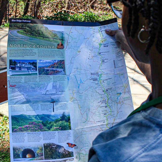 A woman standing outdoors looking at a handheld map