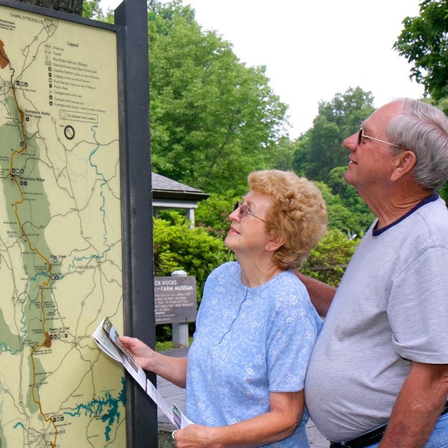 A man and women standing outdoors looking at an exhibit map