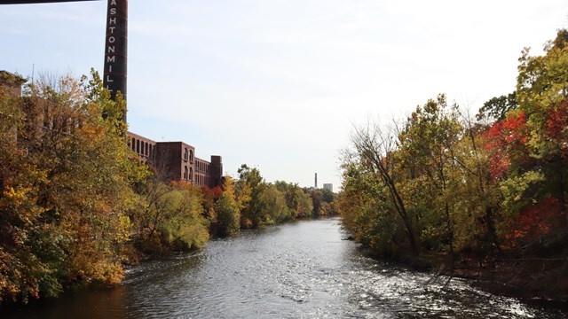 Blackstone River with large brick mill to left bank and fall foliage