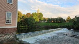Photograph of the Slater Dam with church in the background and Slater Mill on the left of the screen