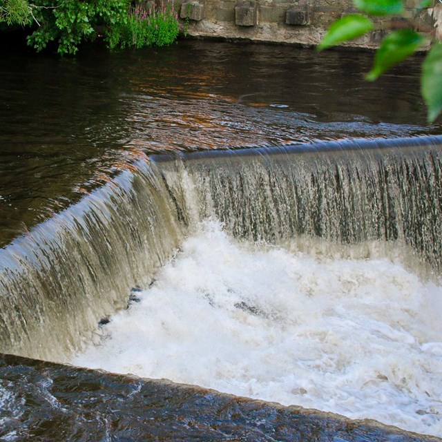Side view of water rushing off a ledge in the Blackstone River known as the Pawtucket Falls