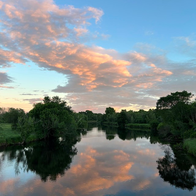 Blackstone River at sunset with trees and grass on either side