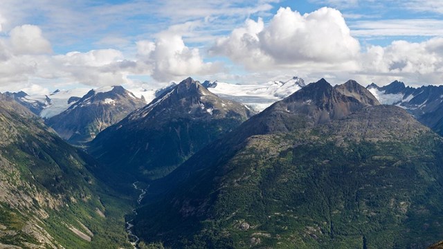 a mountain range with green slopes that transition to white-capped summits.