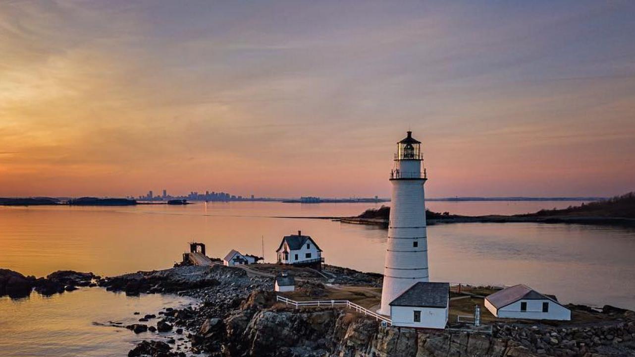 An island with a white lighthouse during a sunset