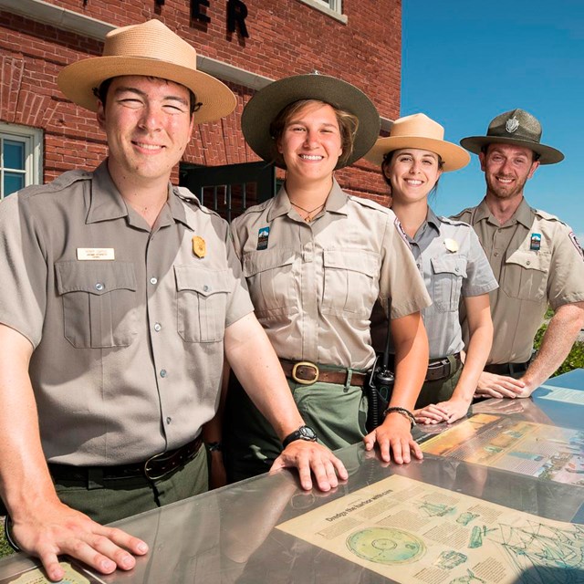 Four rangers, representing both NPS and DCR, stand at an outdoor information table.