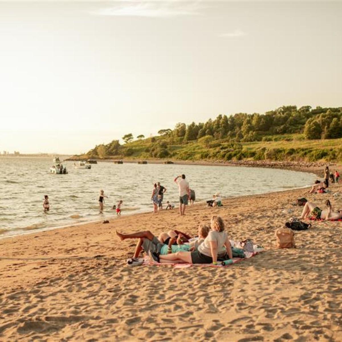 View of the Spectacle beach at sunset with people on the beach and swimming in the water