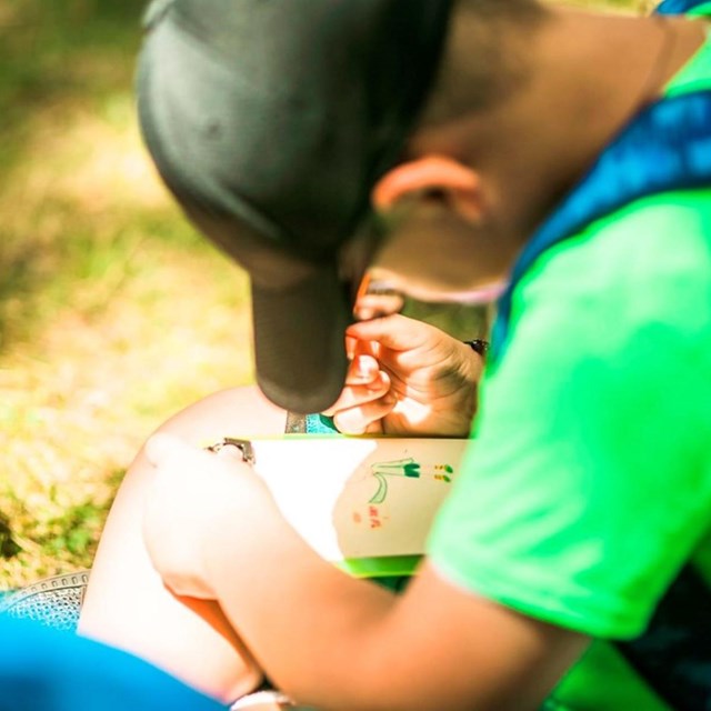 A kid sitting on the ground looking down at an activity he is working on