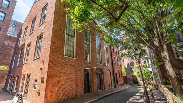 Three story red brick building with large, panned windows. 