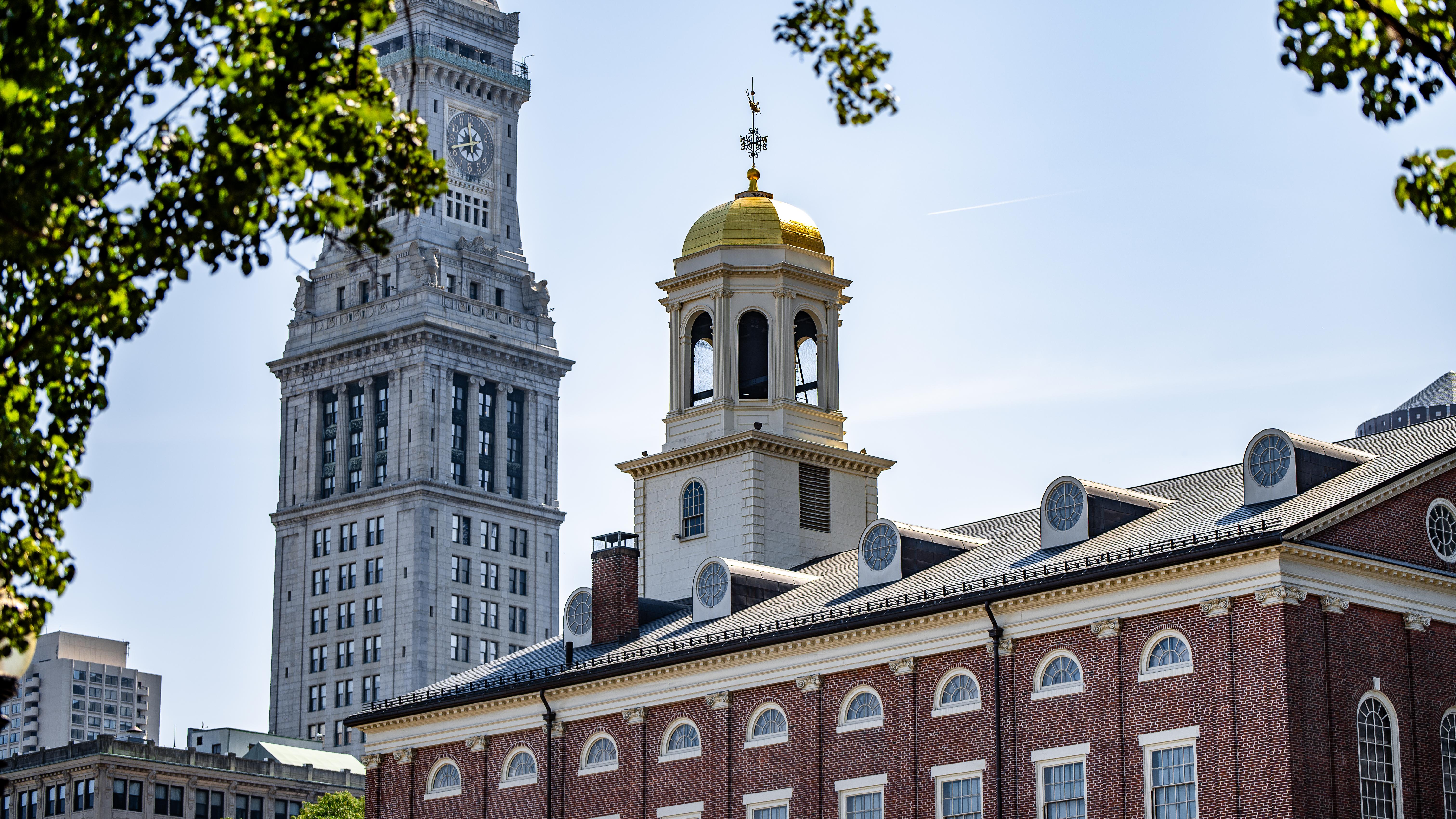 The upper levels and roof of Faneuil Hall with its brick walls, white cupola, and gilt dome.