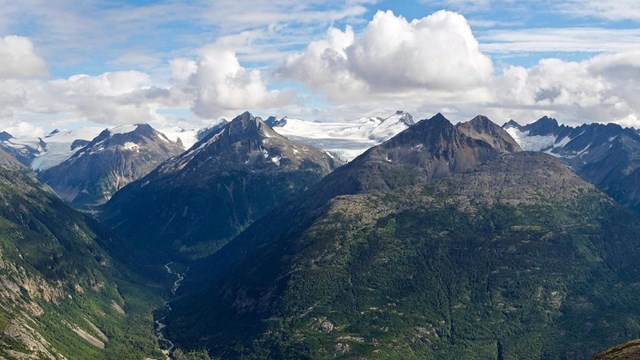 mountain range with green slopes that transition to white-capped summits