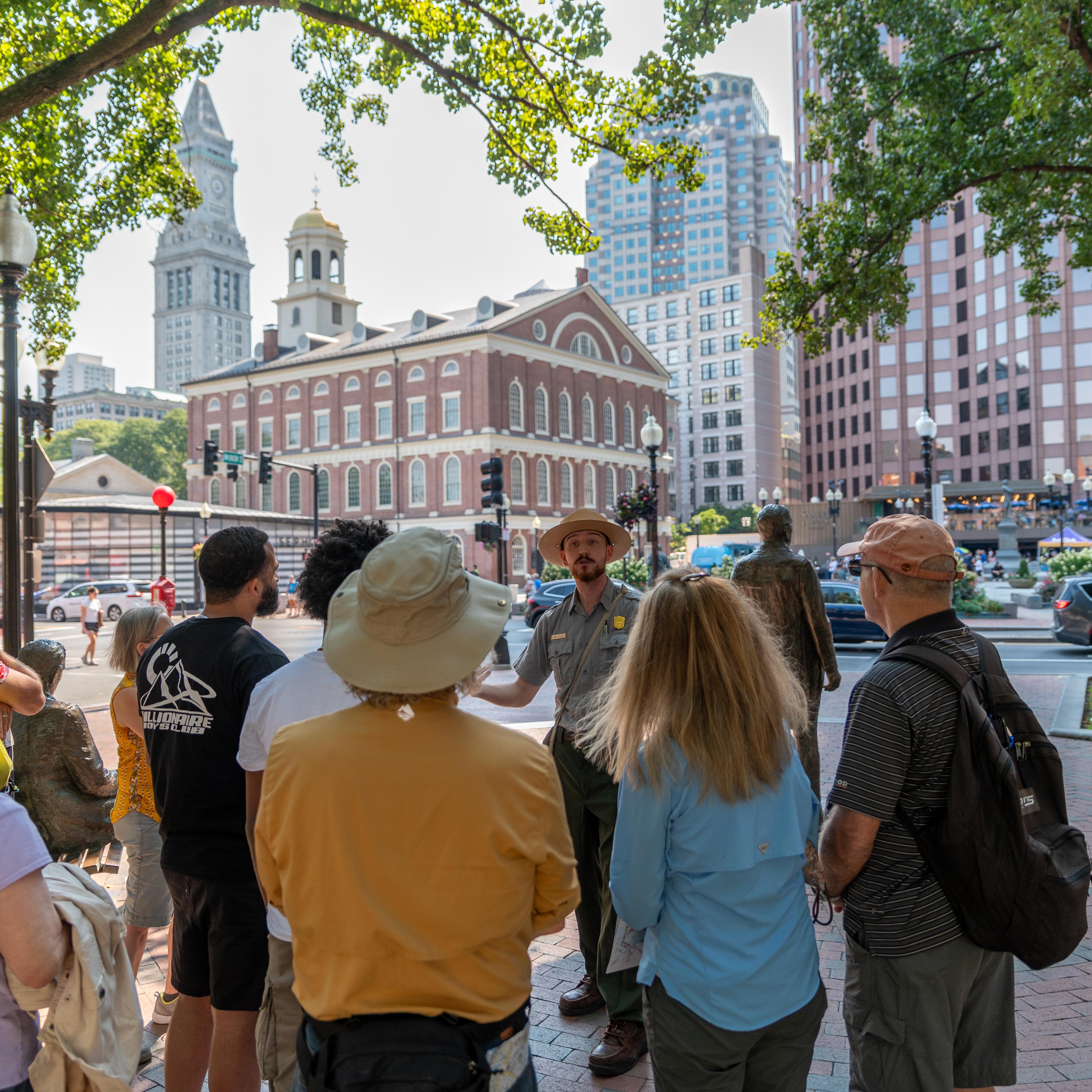 Ranger giving a tour to the public. Faneuil Hall stands in the background.