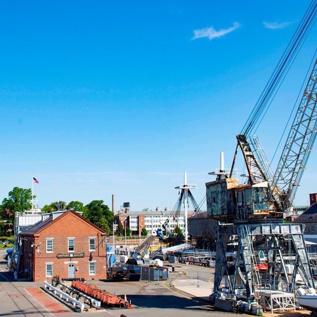 A crane and buildings at a navy yard. 