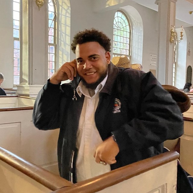 man listening to an audio tour standing in a pew.