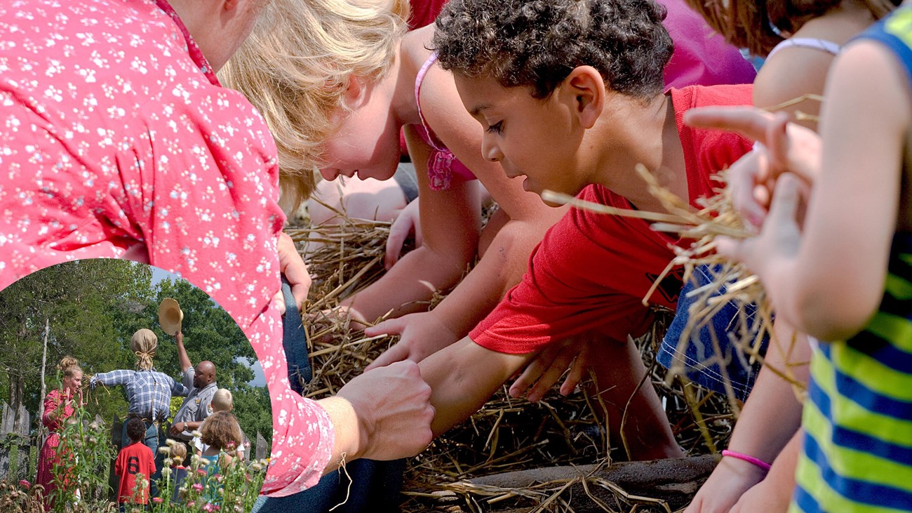 A group of children crouch on the ground gathering straw. 