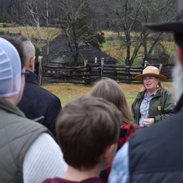 A park ranger in a flat hat speaks with a group of visitors.