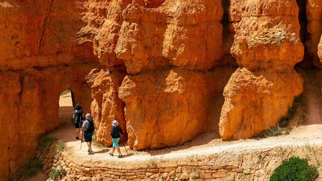 Hikers approach an archway on a hike.