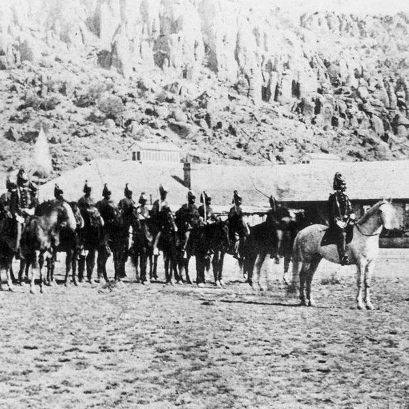 Several army soldiers on horses pose for a photo