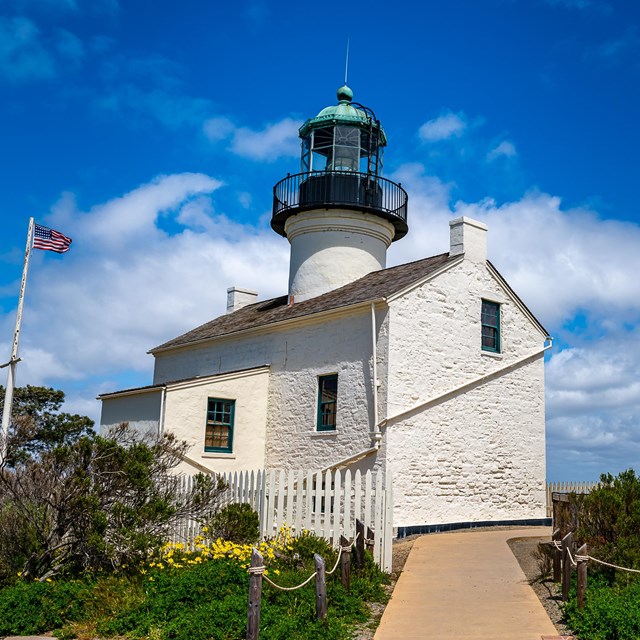 A photo of the Old Point Light House. Two buildings. One with a lighthouse tower.