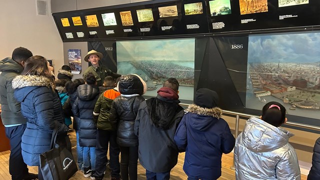 A park ranger giving a talk to a group of children in front of an exhibit