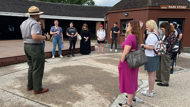 A Park Ranger talking in front of a group of people outside near a Park Store building