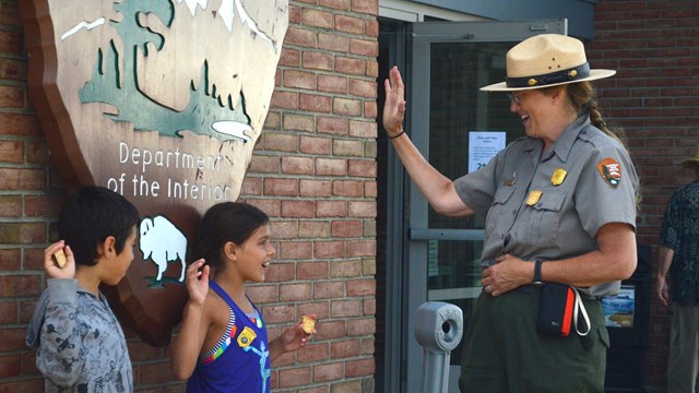 A ranger administers a junior ranger oath to two young park visitors.