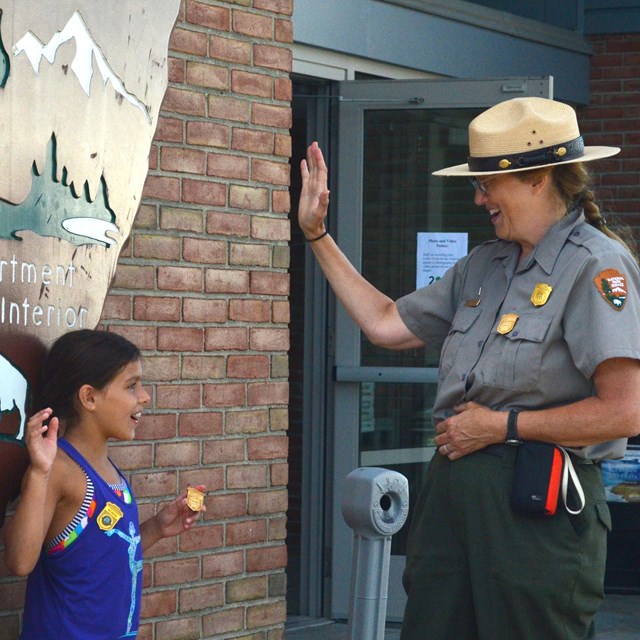 A ranger administers a junior ranger oath to two young park visitors.