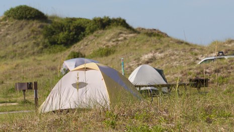 Tents and grill at campsites near the dunes.