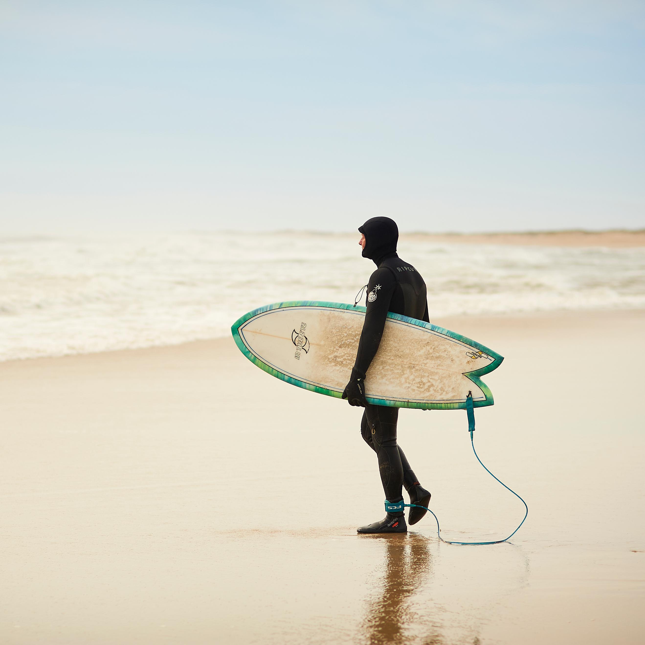 a surfer holding a board walking towards the ocean