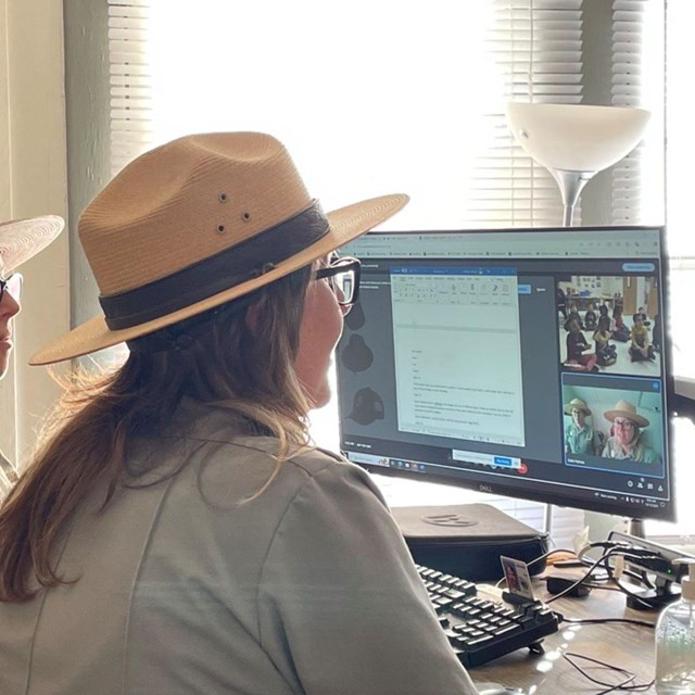 Two rangers sit at computer screens delivering a virtual program.