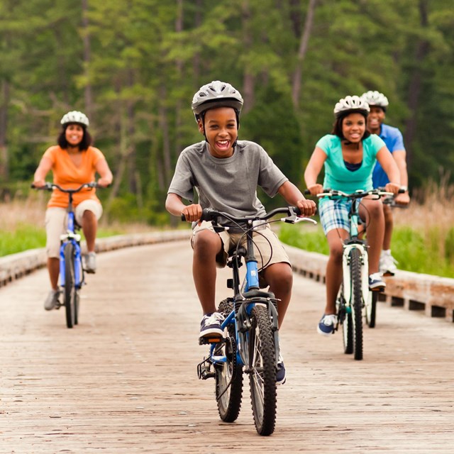A family rides bikes on a boardwalk near Jamestown, Virginia. 