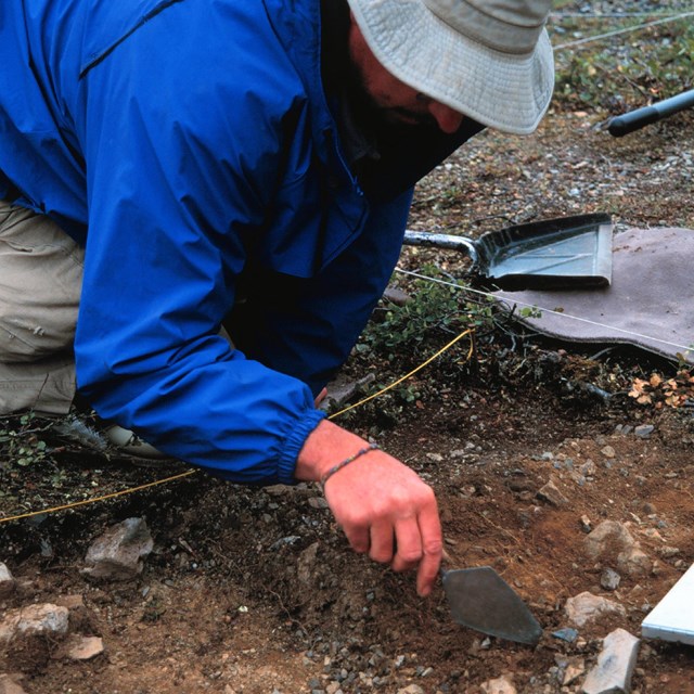 Archaeologist digs in a plot with a small shovel