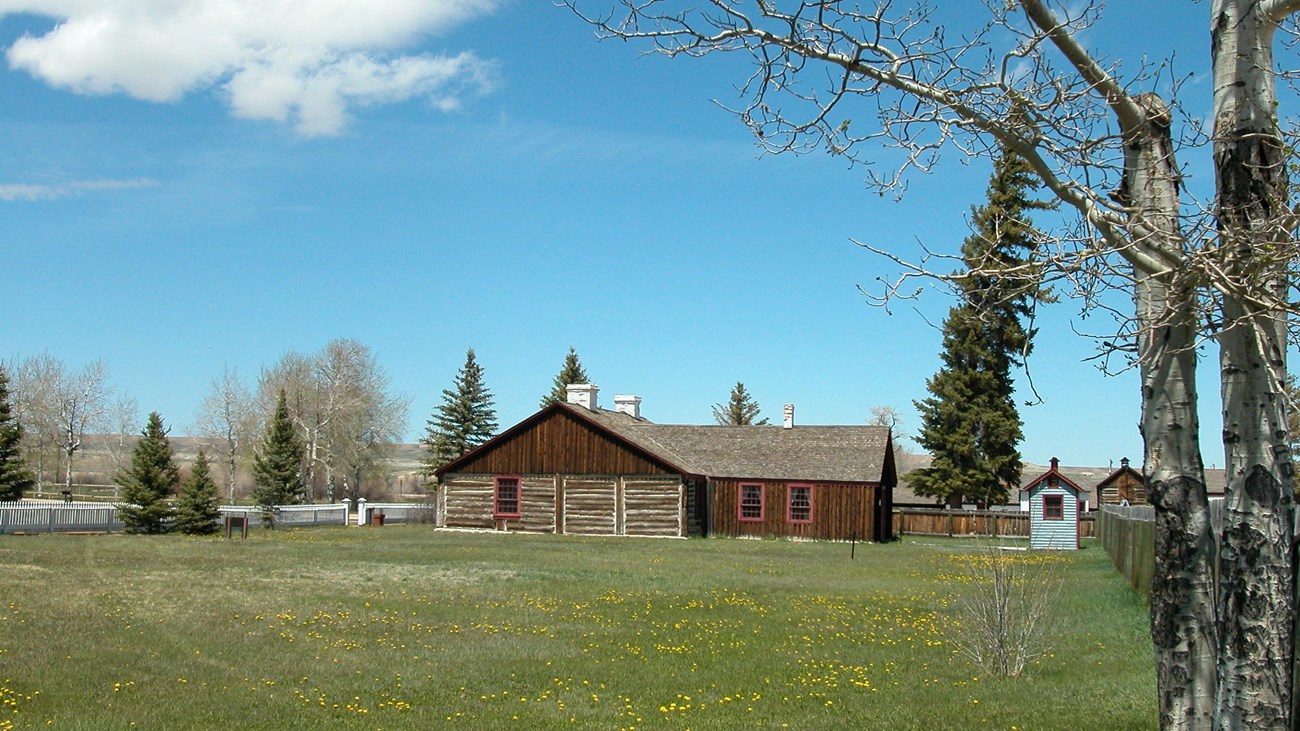 A historic log fort sits across a grassy field.