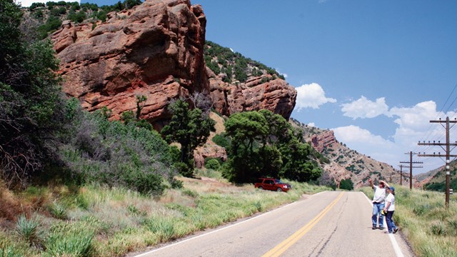 A road leads through a red-rock, steep walled canyon.