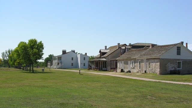 A historic wooden fort in a grassy field.