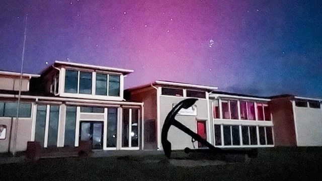 Harkers Island Visitor Center with an anchor infront of the building. Northern lights above building
