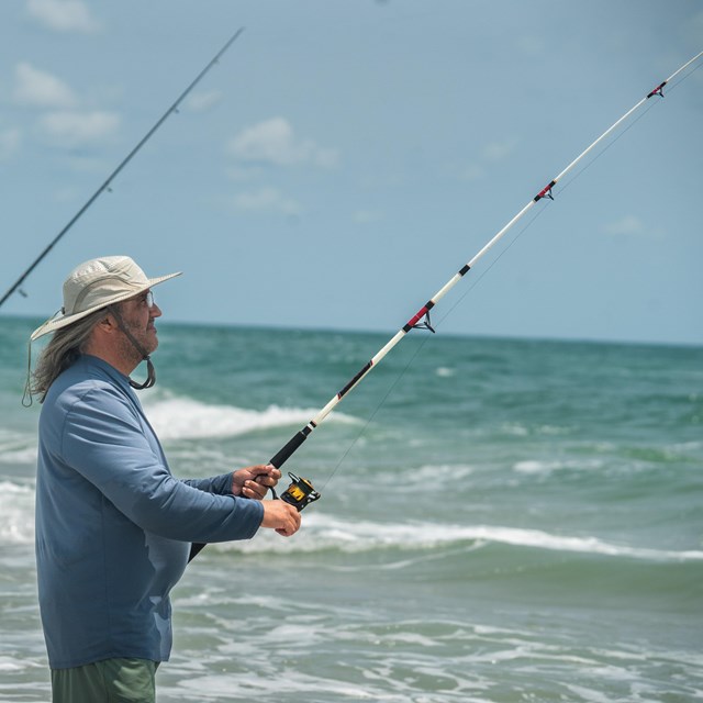 two people standing in water fishing