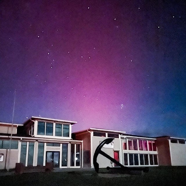 Harkers Island Visitor Center with an anchor infront of the building. Northern lights above building