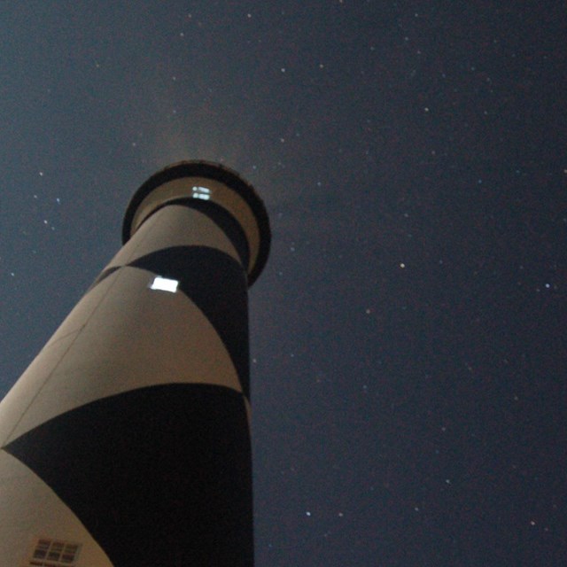 The Cape Lookout Lighthouse against a star-filled sky.