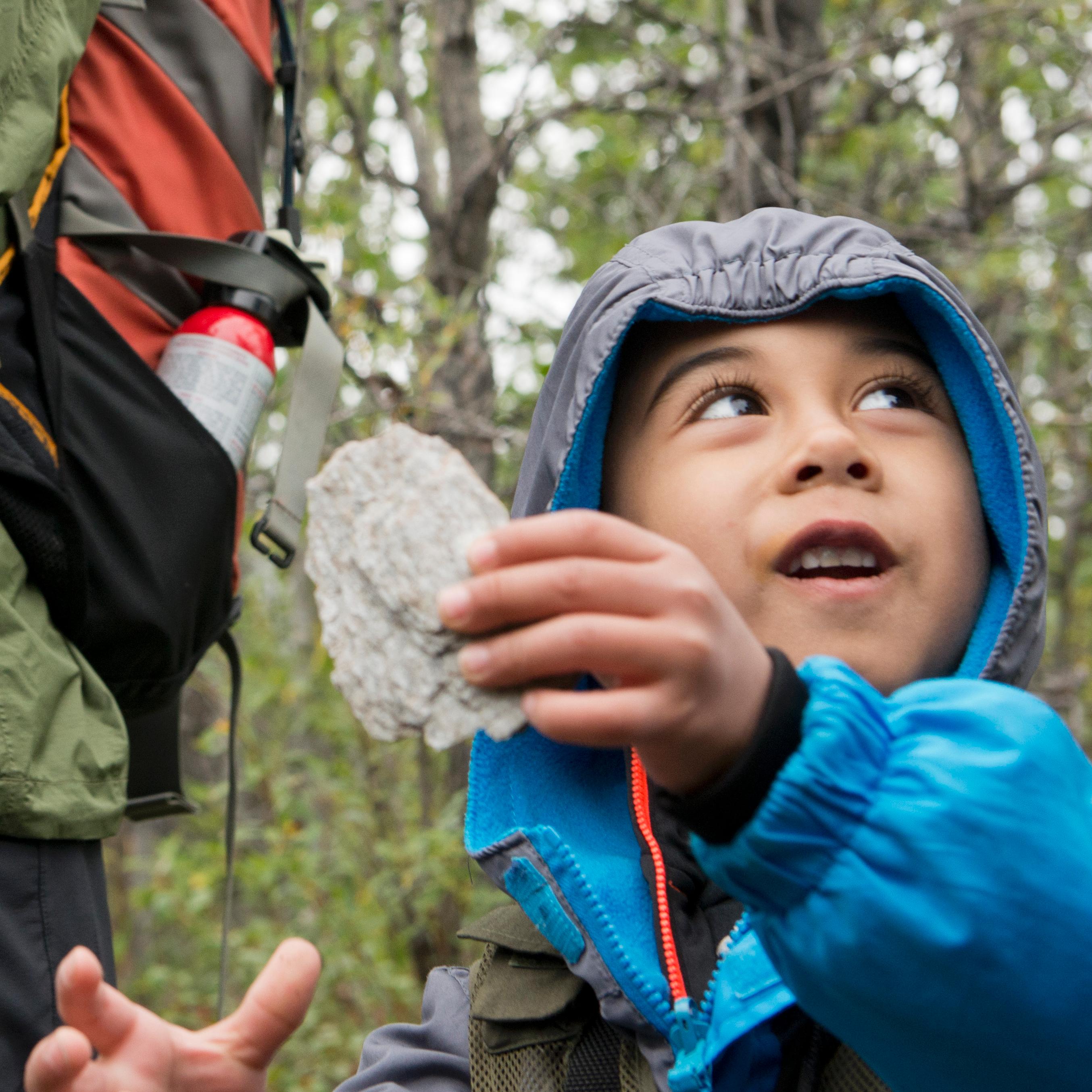 A man and children hover around a fire grate to light a campfire.