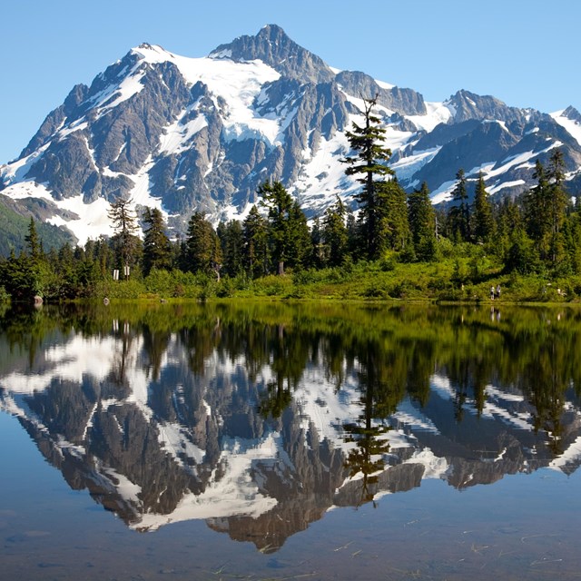 A snowy mountain is reflected in a mountain lake