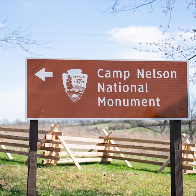 Camp Nelson National Monument direction sign in front of split rail fence.