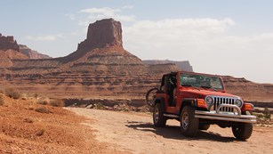a Jeep driving on a flat, rocky road