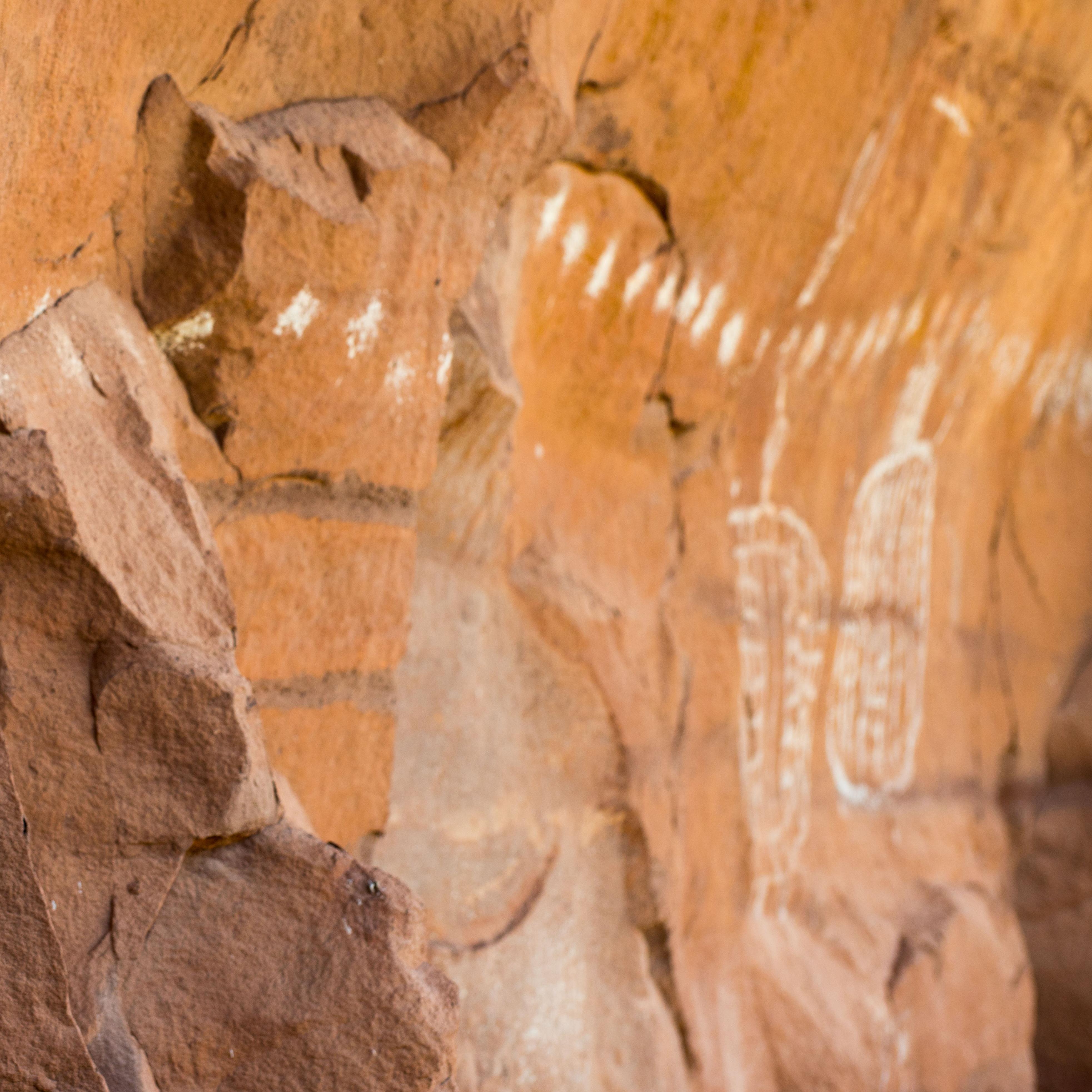 a row of white dots and shapes painted on a rock wall