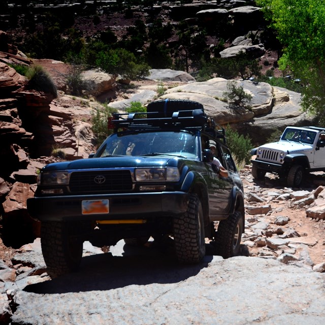 A blue SUV drives up a rocky slope