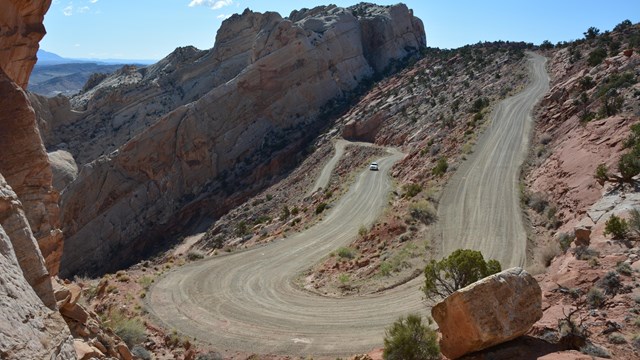 Gravel switchbacks and car in dramatically uplifted landscape.