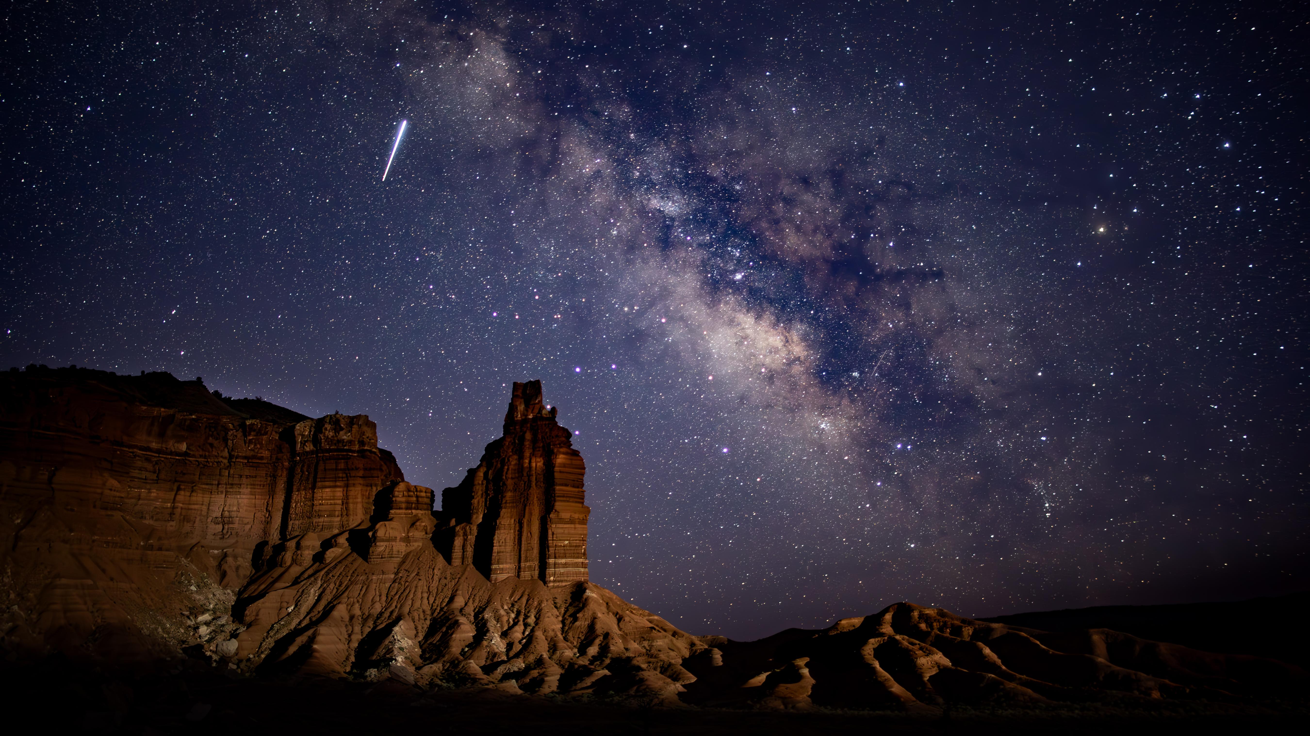 Photo of the Milky Way over Chimney Rock. Several streaks of light from meteors fly across the sky.