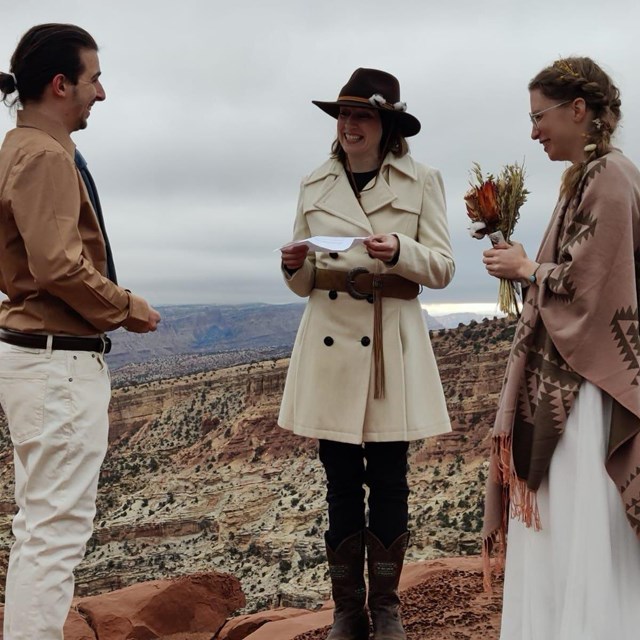 Man and woman getting married in front of red and white canyon, cloudy winter sky. 