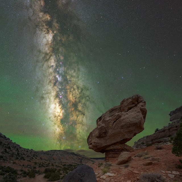 A balanced rock sits in front of a starry night sky.